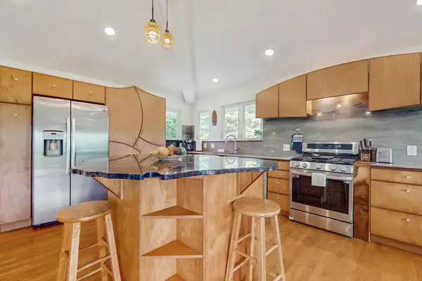 The kitchen features light wood cabinetry paired with a dark granite countertop