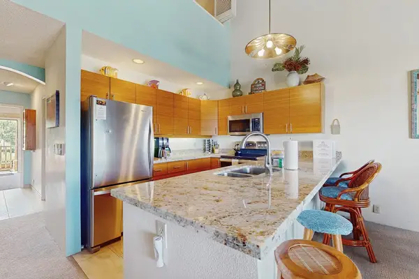 Bright galley kitchen features cabinetry polished counters and practical appliances