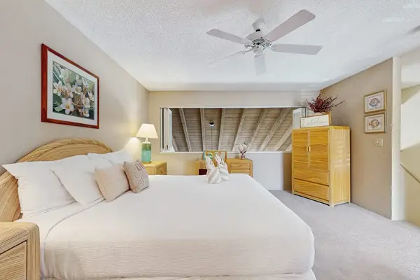 First Bedroom showcases king bed nightstands artwork and tropical details