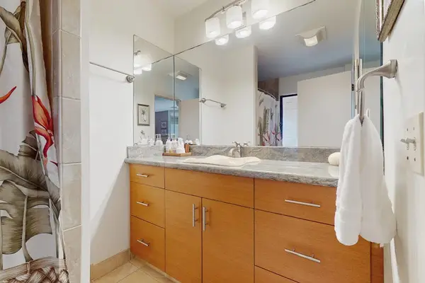 Full Bathroom vanity features wood cabinetry wide counters and mirrors