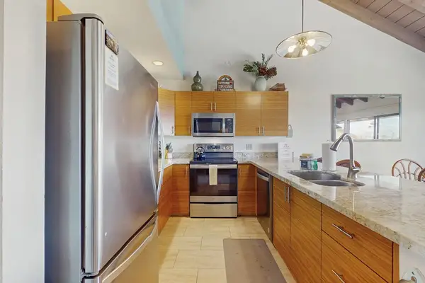 Kitchen island offers generous workspace beside stools and bright cabinetry