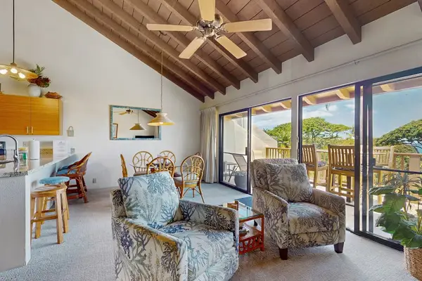 Sunlit living room opens onto balcony with tropical garden views