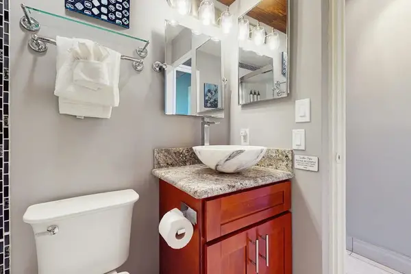 Spotless bathroom presents a vessel sink, mirror, and storage cabinet