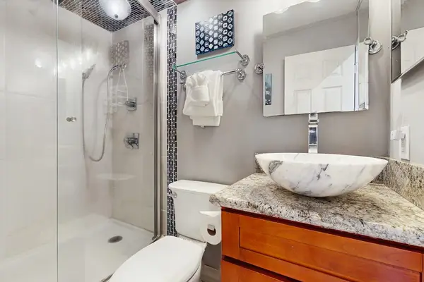 Modern bathroom includes a glass shower, vanity, and fresh fixtures