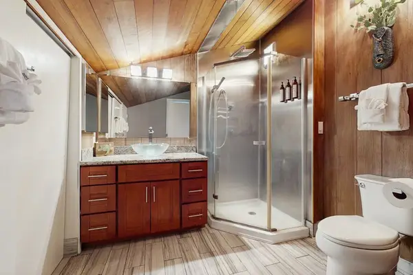 Spacious Bathroom offers warm cabinetry, shower fixtures, and practical storage