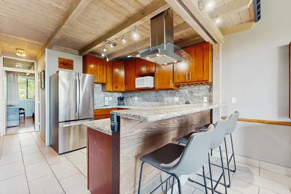 Modern kitchen features wood cabinetry, island seating, and stainless appliances