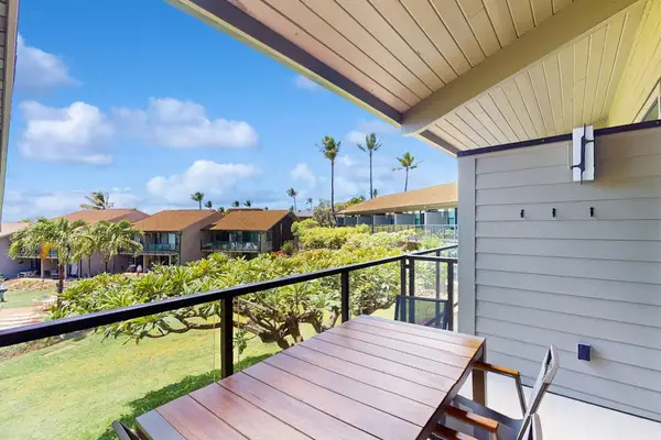 Covered balcony overlooks green lawns, palm trees, and distant ocean