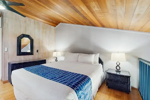 Cozy bedroom features comfortable bedding, wood ceilings, and bedside lamps