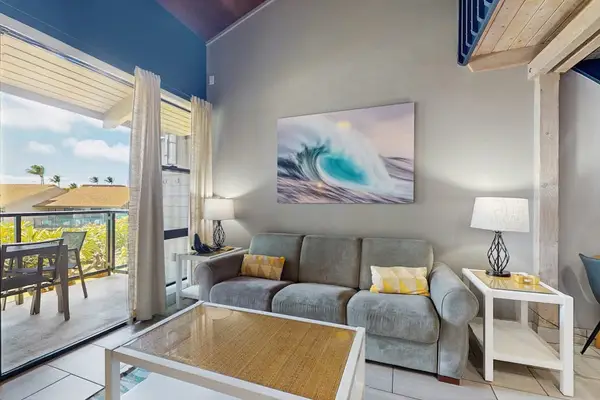Ocean-view living room features comfortable seating, artwork, and bright windows