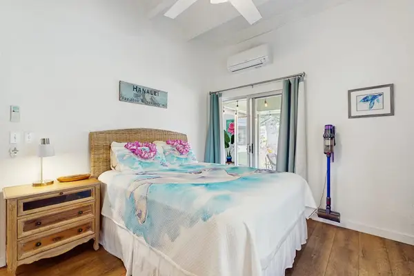 Sunlit bedroom showcases a neatly made bed, bedside table, and soothing decor