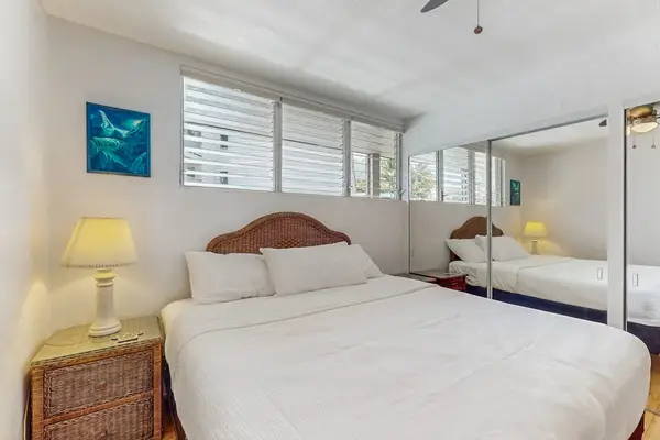 Bedroom features queen bed, mirrored closet, lamps, and artwork