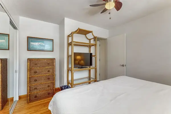 First bedroom shows bed, dresser, ceiling fan, shelving, and artwork