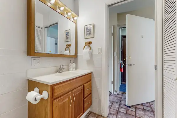 Bathroom vanity area includes mirror, sink, toiletries, towels, and doorway