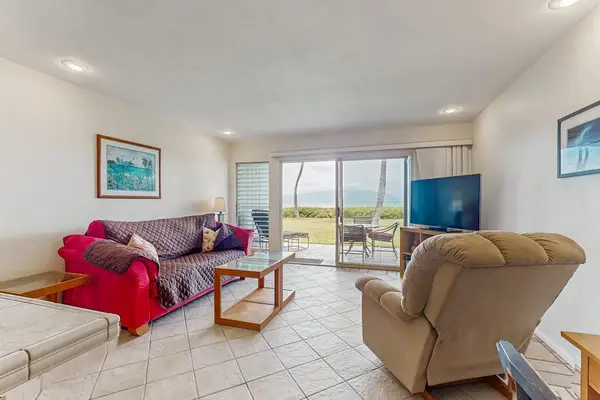Living room seating faces television and bright ocean-facing sliding doors