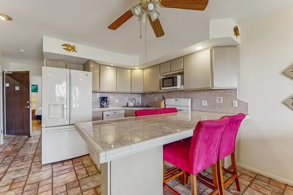 Kitchen island anchors pink stools, appliances, counters, and upper cabinets