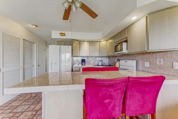 Dining counter offers pink chairs, cabinetry, ceiling fan, and windows