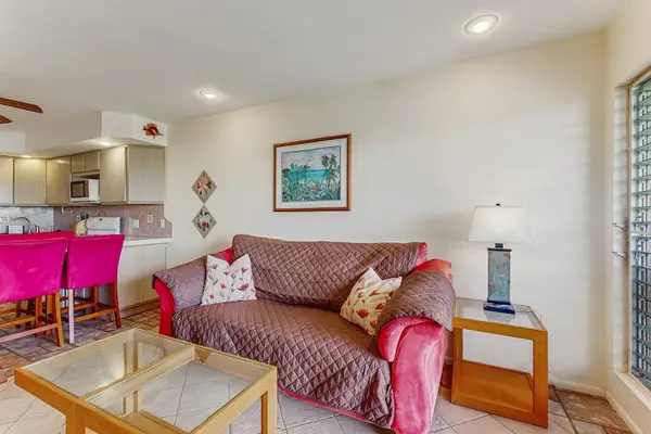 Living room includes patterned sofa, accent chairs, counter, and artwork