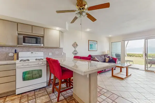 Open kitchen features island seating, appliances, cabinetry, and ocean-facing windows