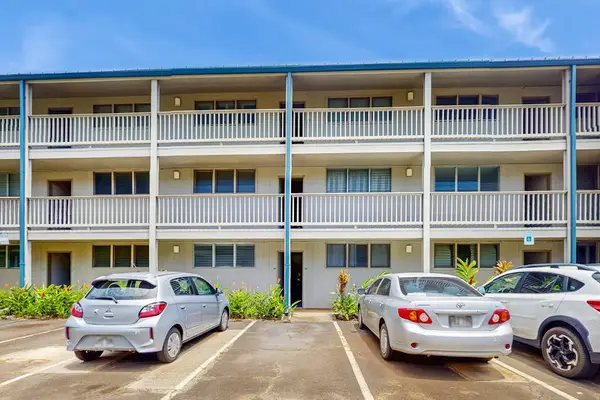 Resort building displays balconies, palm landscaping, parking spaces, and skies