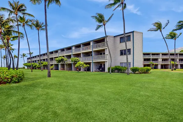 Apartment building stands among palms, lawns, and landscaped resort grounds