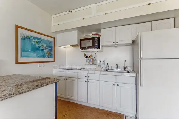 Kitchen workspace includes counters, appliances, cabinetry, and colorful artwork nearby