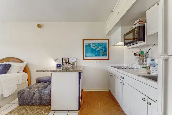 Open kitchen features counters, appliances, artwork, seating, and television nearby