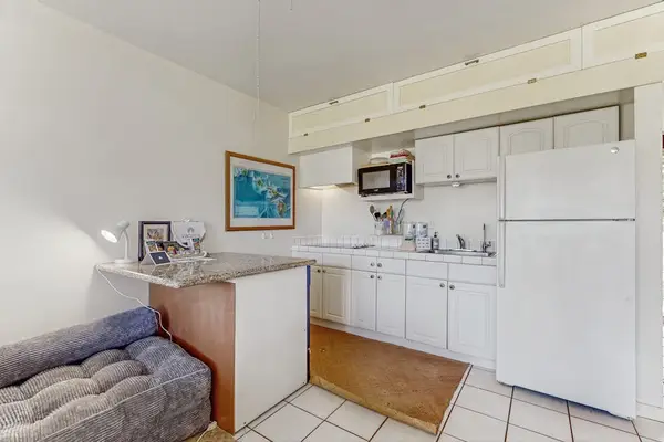Compact kitchen provides refrigerator, counters, cabinets, and adjoining living space