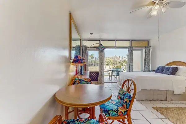 Studio seating area includes table, chairs, queen bed, and artwork