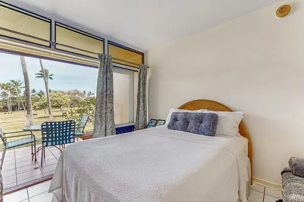 Studio bed faces glass doors with ocean views and lamp