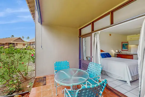 Covered patio includes turquoise chairs, table, sliding doors, and gardens