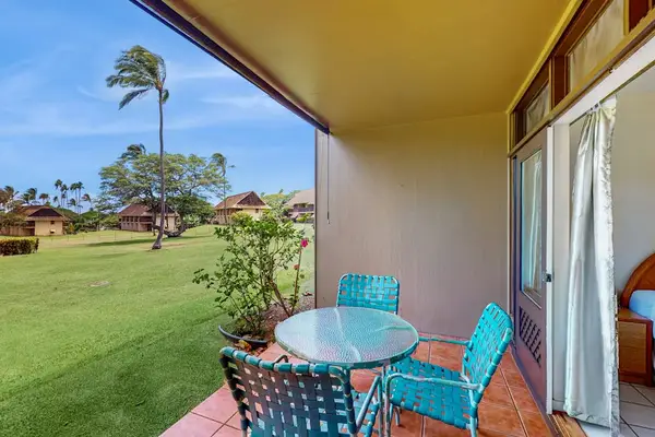 Covered patio offers dining chairs, table, lawn views, and breezes