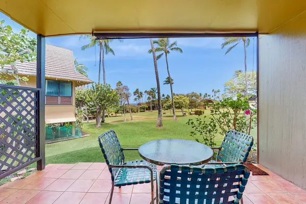 Covered patio dining area overlooks resort gardens, palms, and ocean