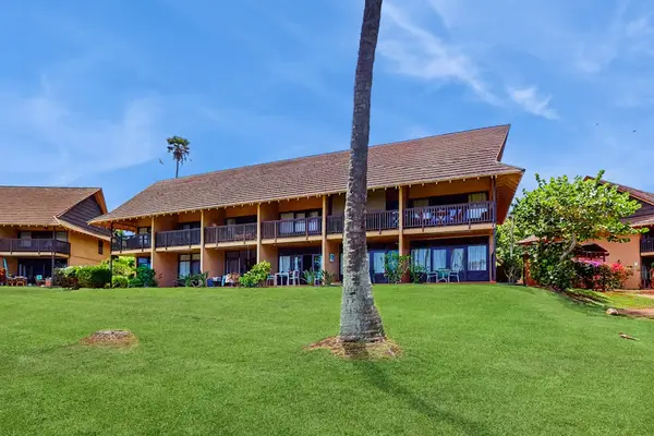 Resort building overlooks broad lawns, palms, balconies, and island skies