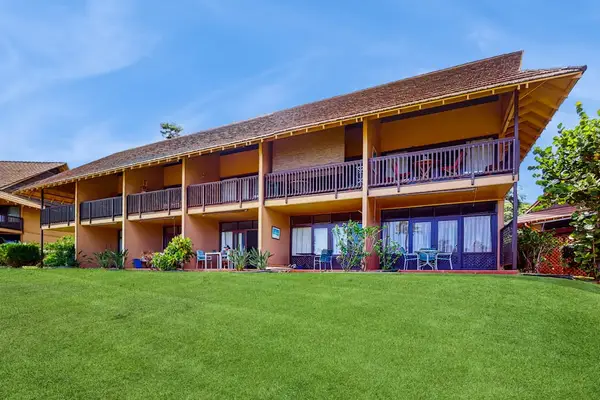 Resort building spans manicured lawn with balconies, palms, and grounds
