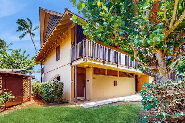 Resort building features balcony, tropical landscaping, lawn, and shaded entrances