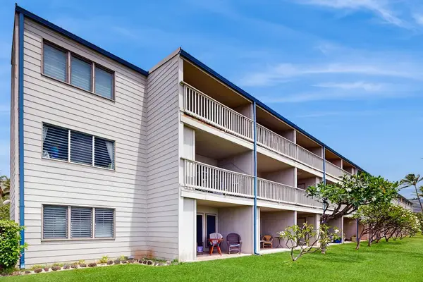 Resort building features balconies, lawns, palms, and sunny island surroundings