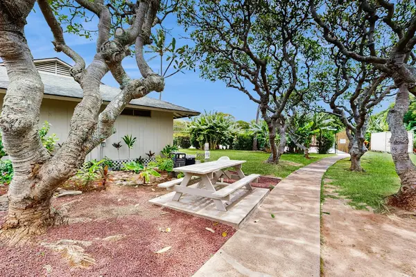 Garden walkway winds past tropical plants, stone paths, and outdoor seating