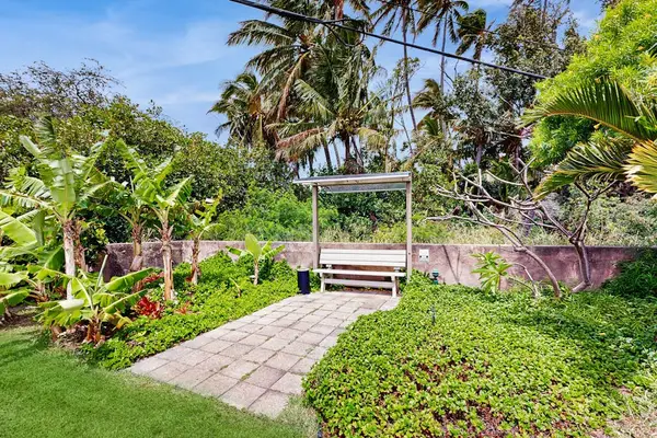 Stone garden path leads through greenery toward shaded outdoor seating