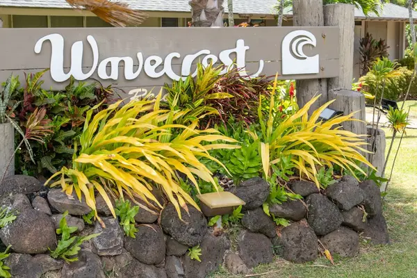 Wavecrest entrance sign sits among volcanic rocks and tropical plants