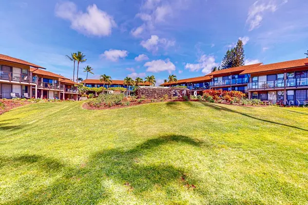 Spacious lawn frames resort buildings, palm trees, and bright skies