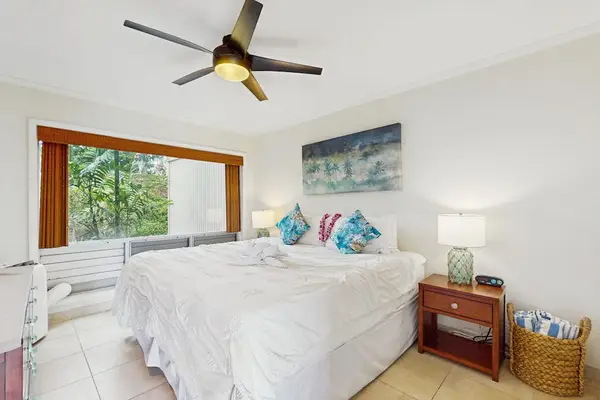 Restful bedroom showcases layered bedding, soft lighting, and tropical artwork