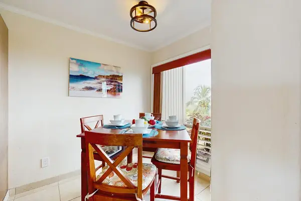 Dining room presents a round table, chairs, and garden views