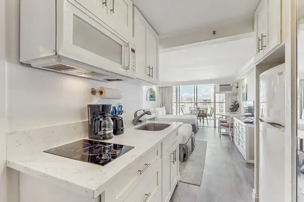An efficient kitchenette comes equipped with an electric cooktop, microwave, coffee maker, and refrigerator.