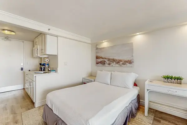 A well-appointed sleeping area offers a comfortable bed, bedside table, compact vanity desk, and coastal decor.