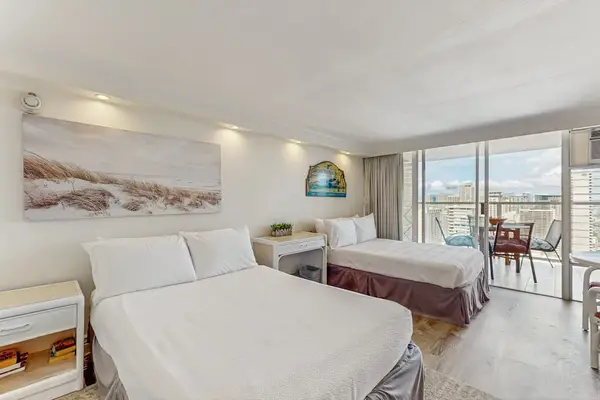 The open-concept studio features two plush beds and direct sliding glass door access to the balcony.