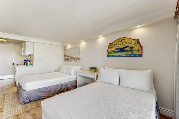 A welcoming sleeping area is outfitted with two comfortable beds, ambient lighting, and tropical wall decor.