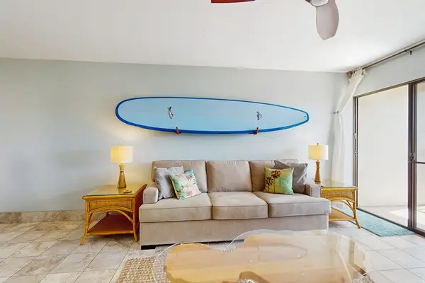 Cozy living room with surf-inspired décor, a flat-screen TV, a comfortable sofa bed, and direct access to the private lanai.