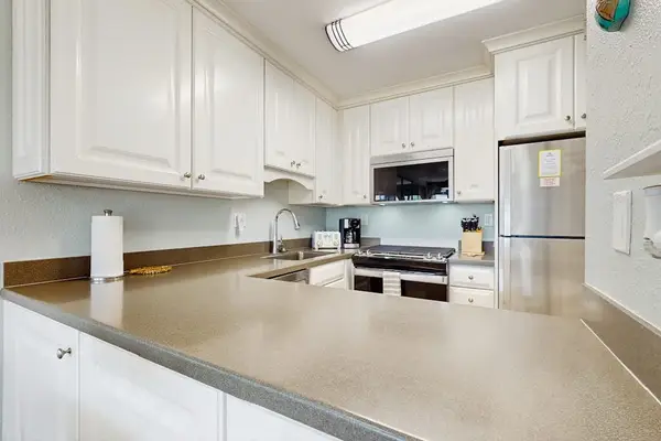 Cozy kitchen with everything you need for home-cooked meals, opening to the dining and living areas with abundant natural light from the sliding doors to the lanai.