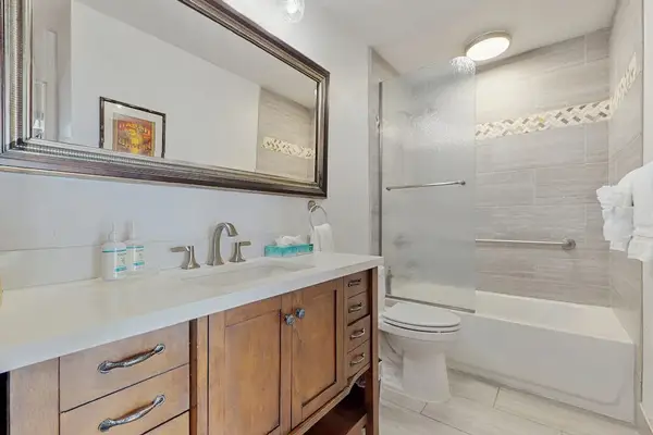 Bright Bathroom Featuring Large Vanity And Tiled Shower Tub
