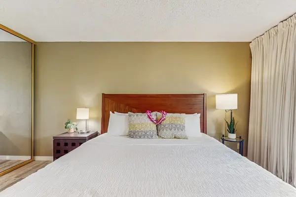 Newly remodeled condo with king bed, ceiling fan and light from the lanai.